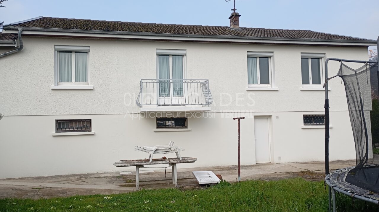 Maison blanche avec balcon et fenêtres.